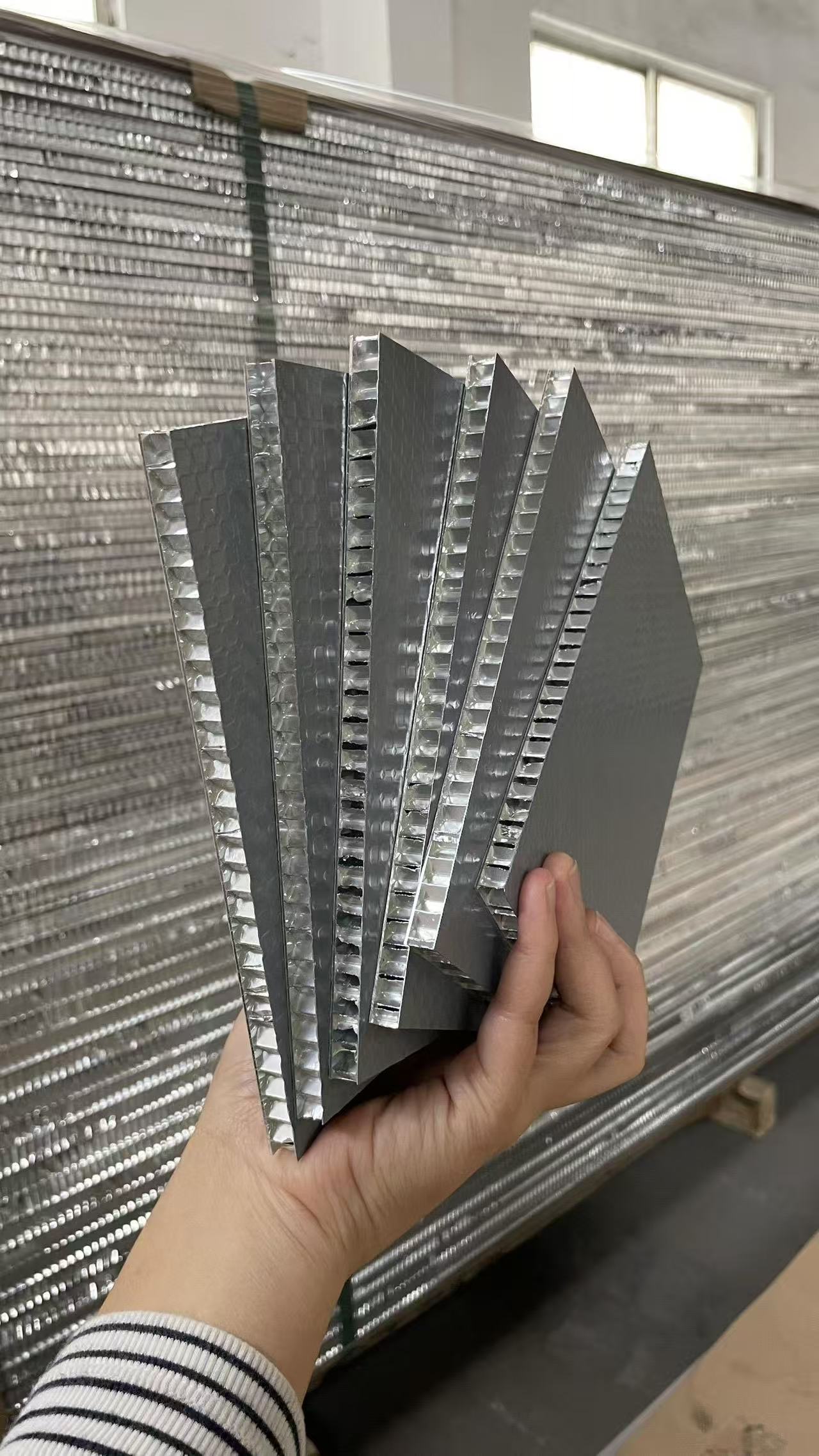 Hand-held aluminum honeycomb panel samples with gray faces and exposed honeycomb cores