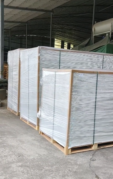 Wrapped panel bundles secured with straps on wood pallets inside a workshop.